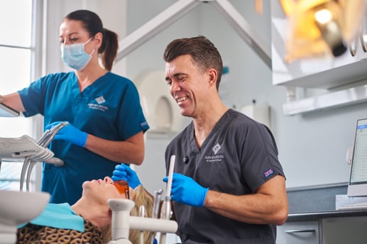 A photograph of a dentist examining a patient with a dental nurse