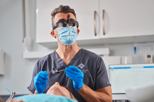 A photograph of a dentist with a dental tool in their hand