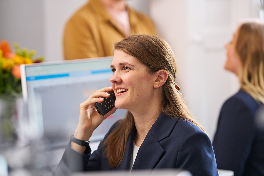 A photograph of a receptionist smiling and using a telephone