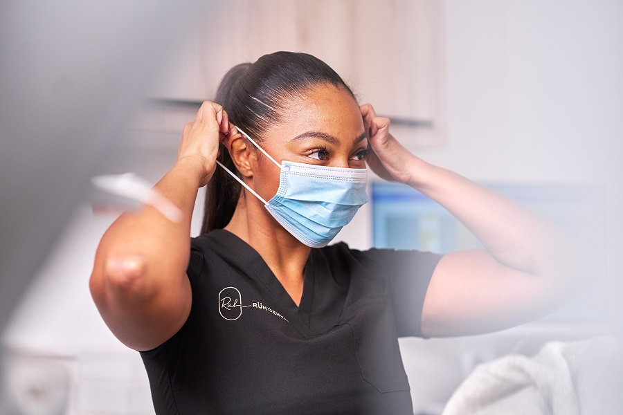 A photograph of a dentist putting on a face mask
